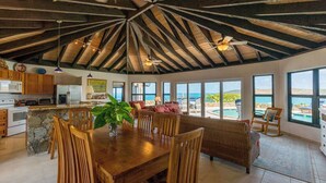 A spacious kitchen with a stone island, wooden dining area, and large windows overlooking a pool.