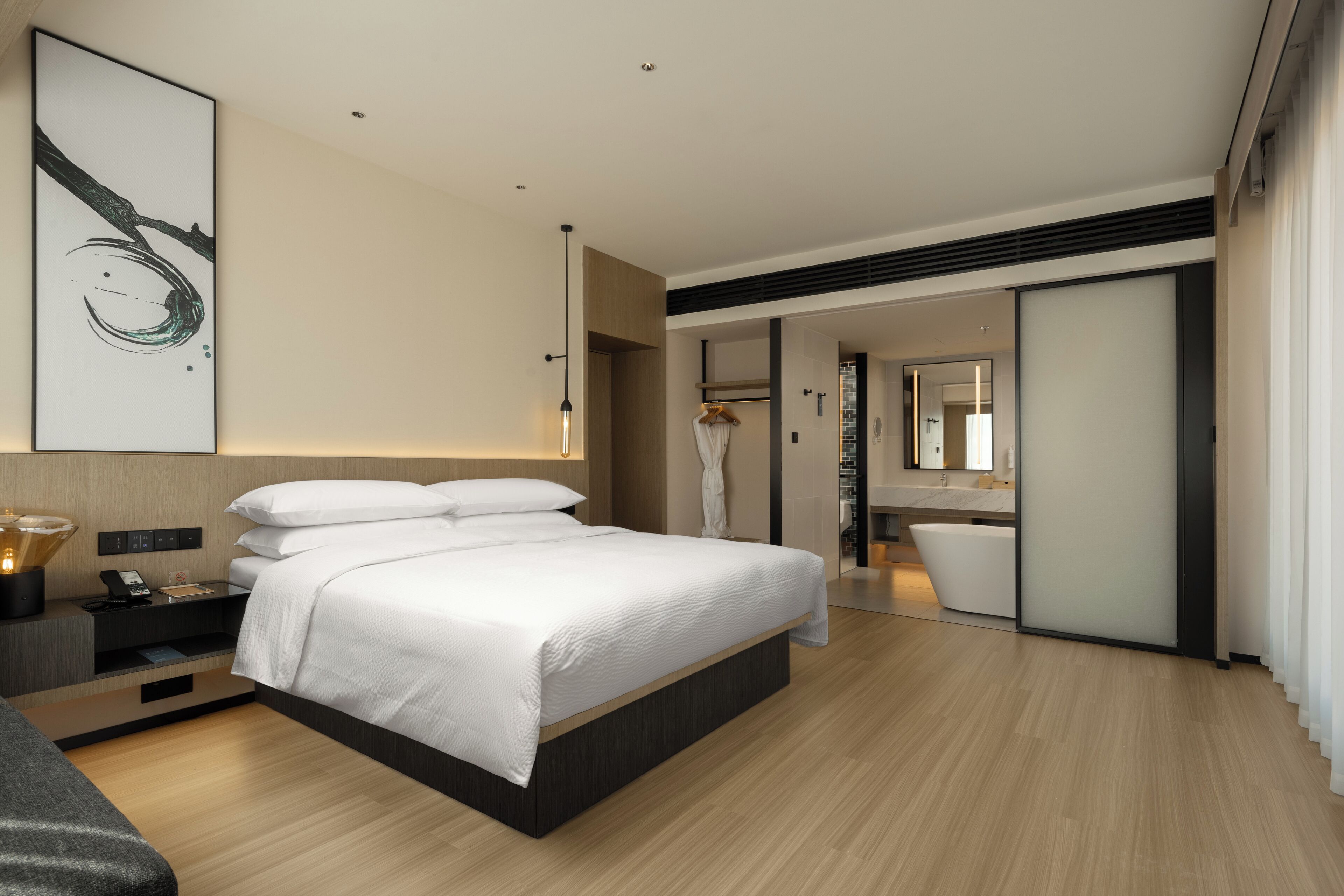 Een moderne hotelkamer met een groot bed, nachtkastjes, een garderobe en een badkamer met een bad.