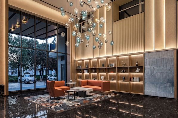 A modern lobby with a seating area, large windows, and a decorative light fixture.