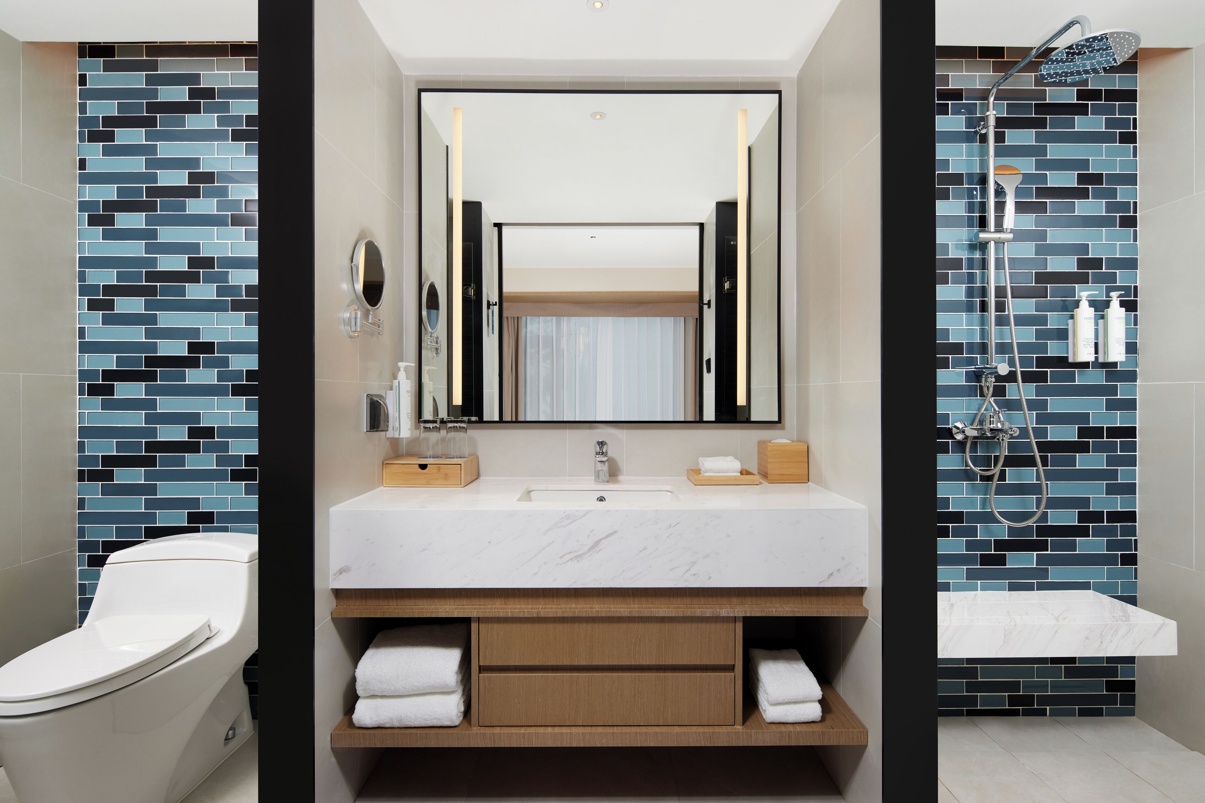 A modern bathroom with a white sink, mirror, and a shower with a handheld showerhead.