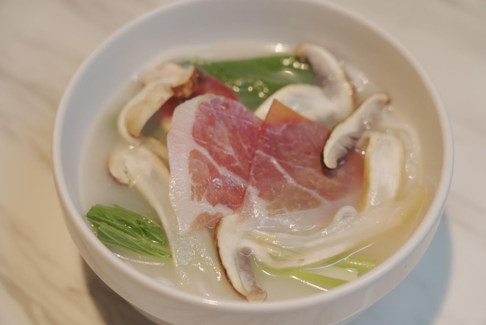 A bowl of soup with meat and vegetables.