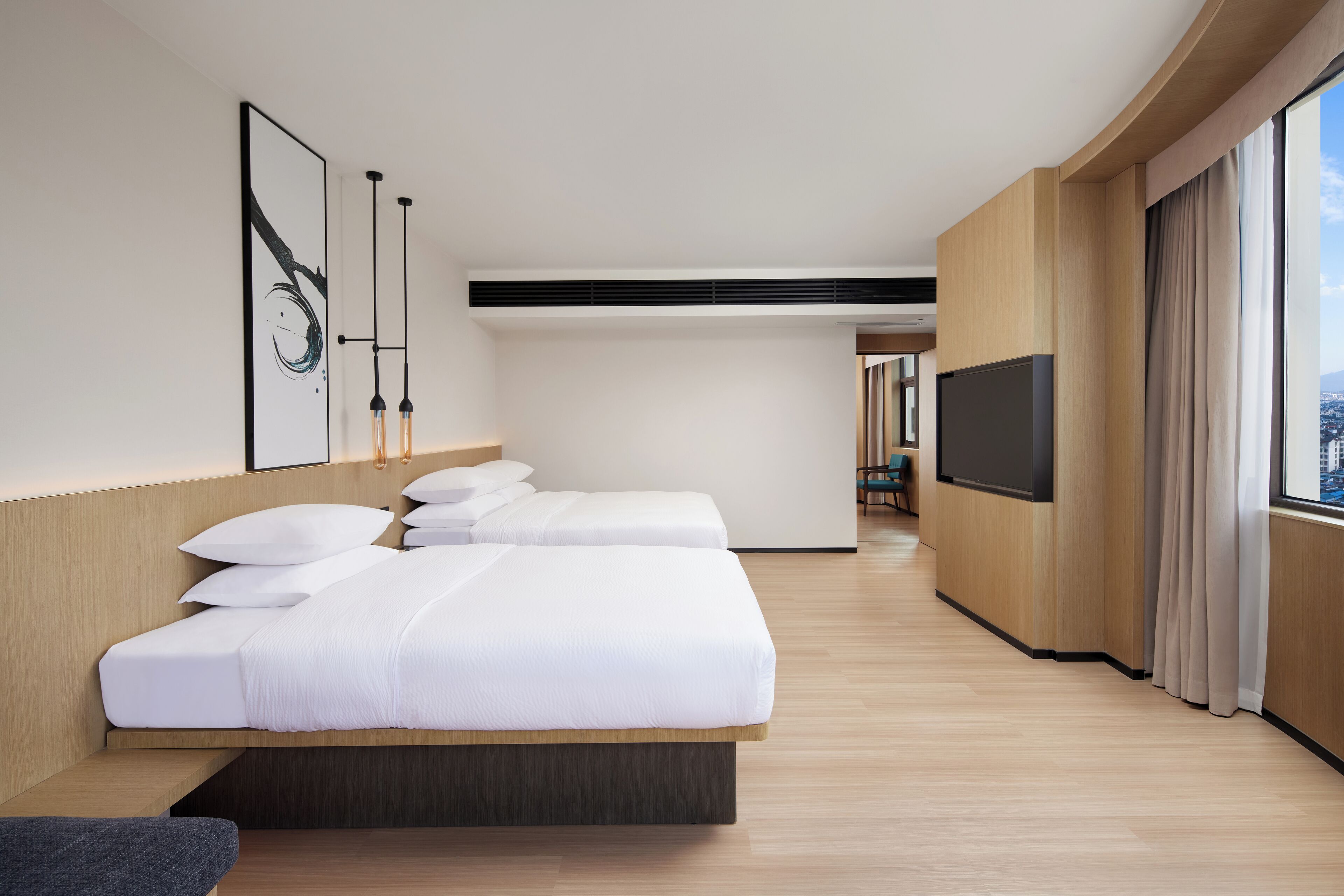 Ein modernes Hotelzimmer mit einem großen Bett, einem Fernseher und Blick auf die Stadt.