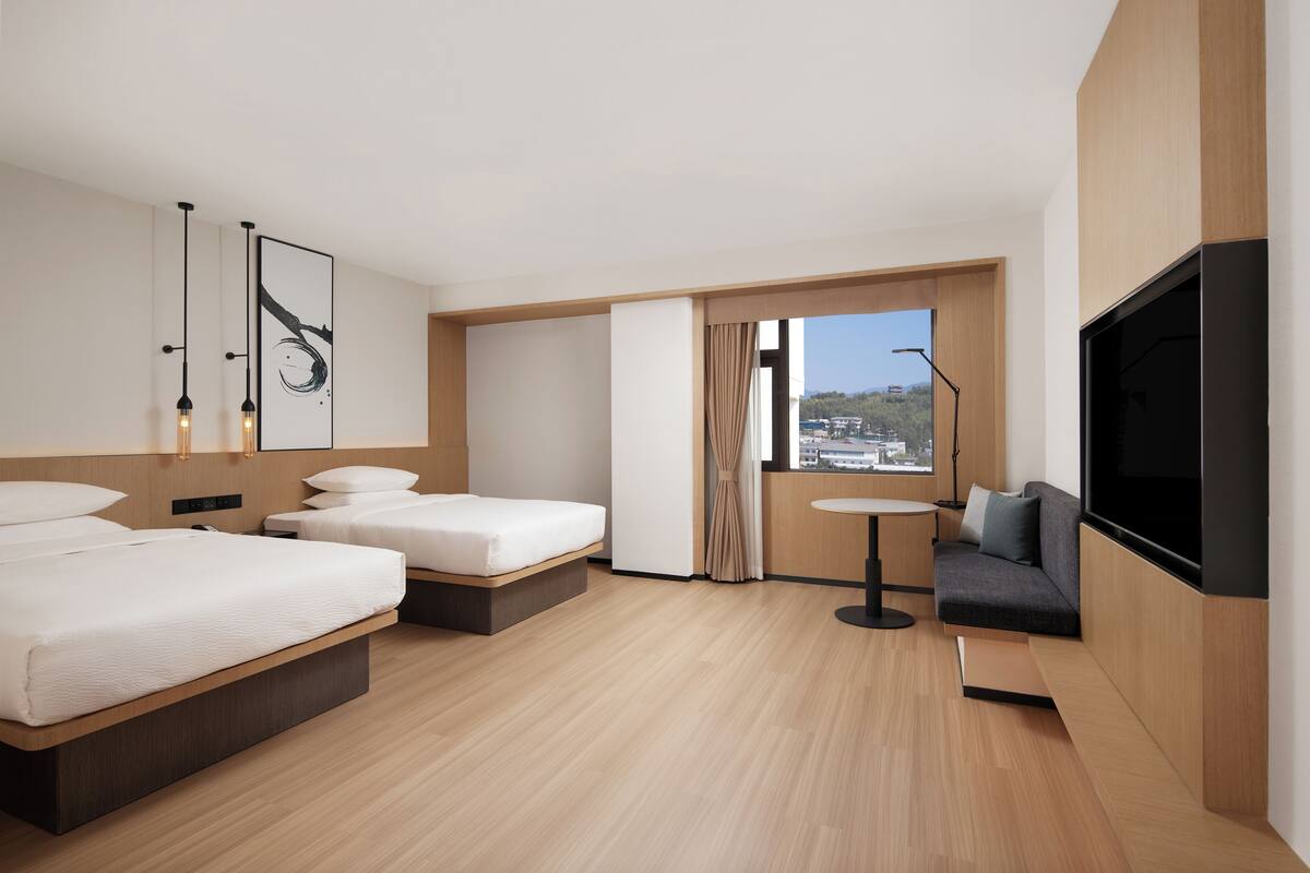 Une chambre d’hôtel moderne avec un grand lit, un canapé, une petite table et un téléviseur.