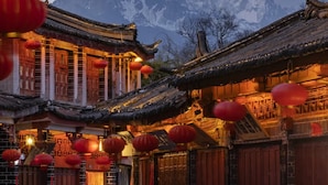 A traditional building with wooden doors and red lanterns, set against a backdrop of snow-capped mountains. - Fairfield by Marriott Lijiang Ancient Town (Lijiang)