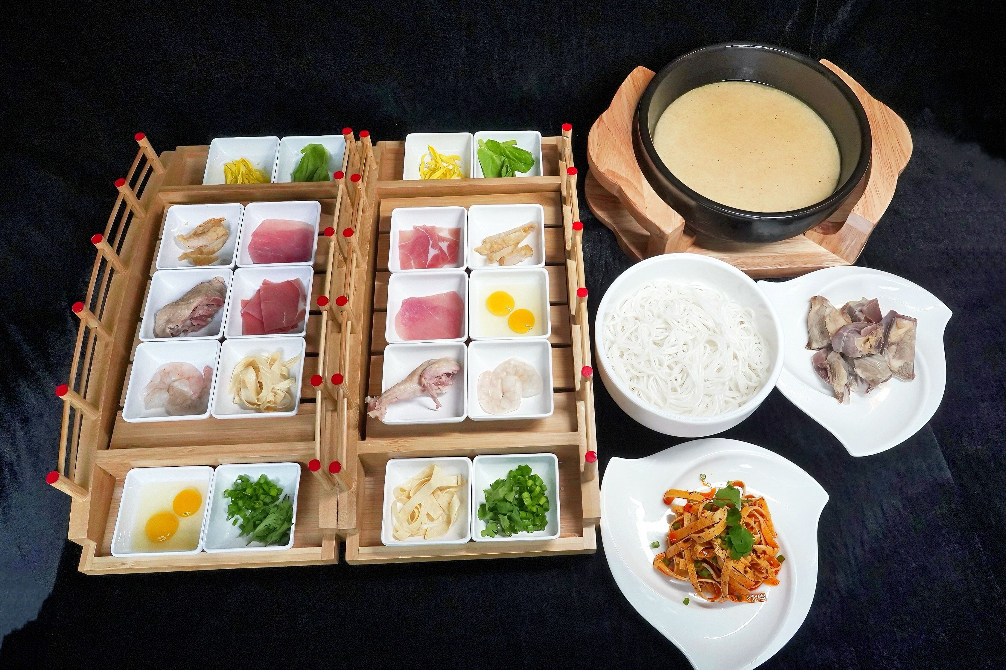 Una bandeja de madera con diferentes alimentos y un tazón de sopa.