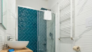 Une salle de bain moderne avec un lavabo blanc, un bidet, des toilettes et une douche à parois de verre.