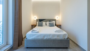 Une chambre d’hôtel moderne avec un grand lit, deux tables de chevet et une fenêtre avec des rideaux.