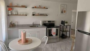 A modern kitchen with white cabinetry, a round dining table, and a stainless steel refrigerator.