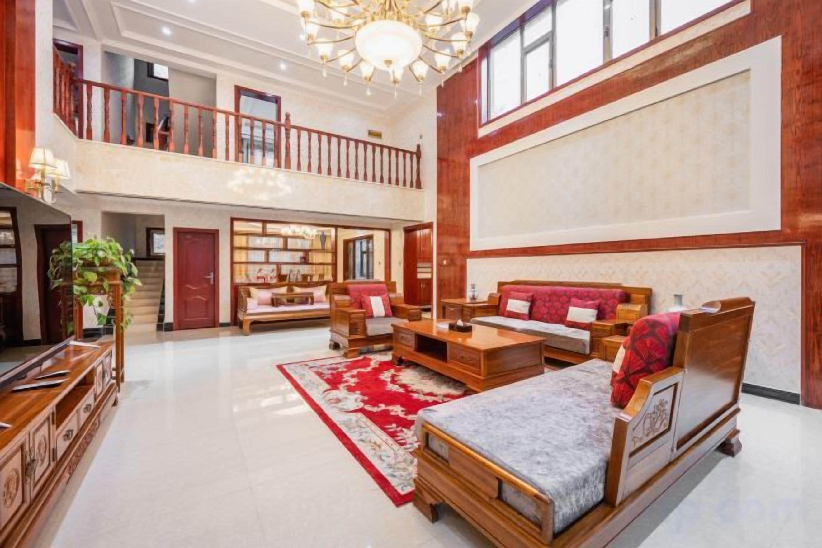 A spacious living area with a high ceiling, a fireplace, and a large window.