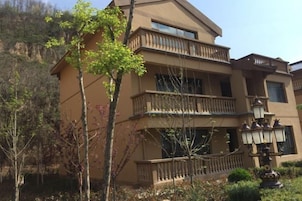 A multi-story building with balconies, a well-maintained garden, and a clear sky.