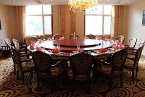 A conference room with a round table, chairs, and a chandelier. - Longhai Hotel (Tanchang)