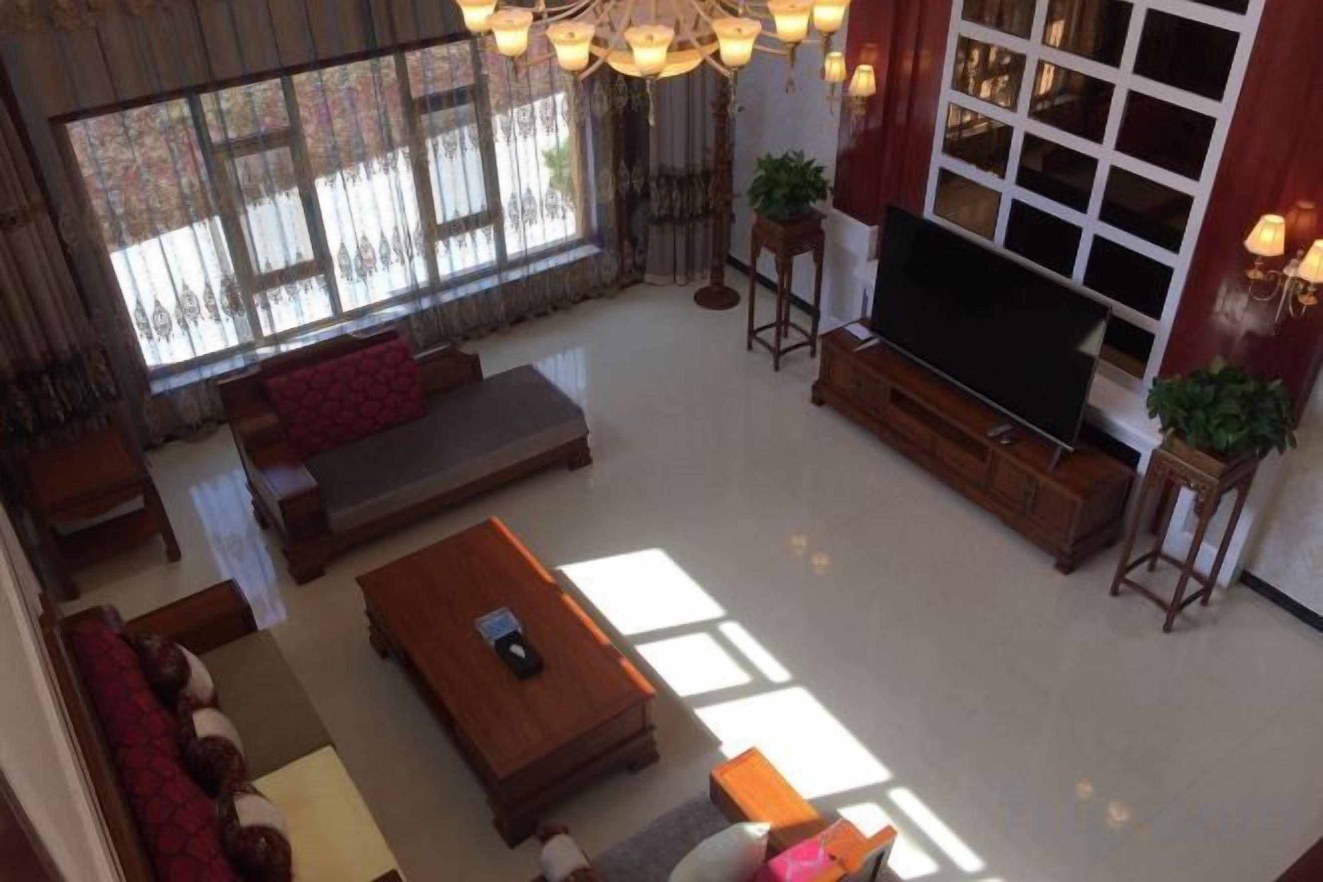 A spacious living room with a large flat-screen TV, comfortable seating, and a large window providing natural light.