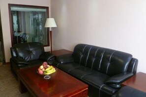 Una habitación con un sofá de cuero negro, una mesa de centro de madera con fruta y una lámpara.