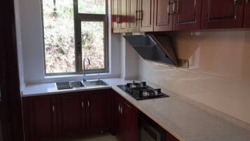 A kitchen with a window, dark wooden cabinets, a countertop, and a stove.