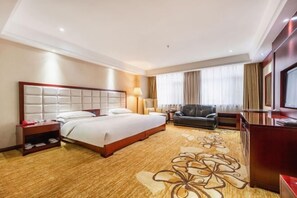 A hotel room with a large bed, a sofa, a desk, and a TV. - Longhai Hotel (Tanchang)