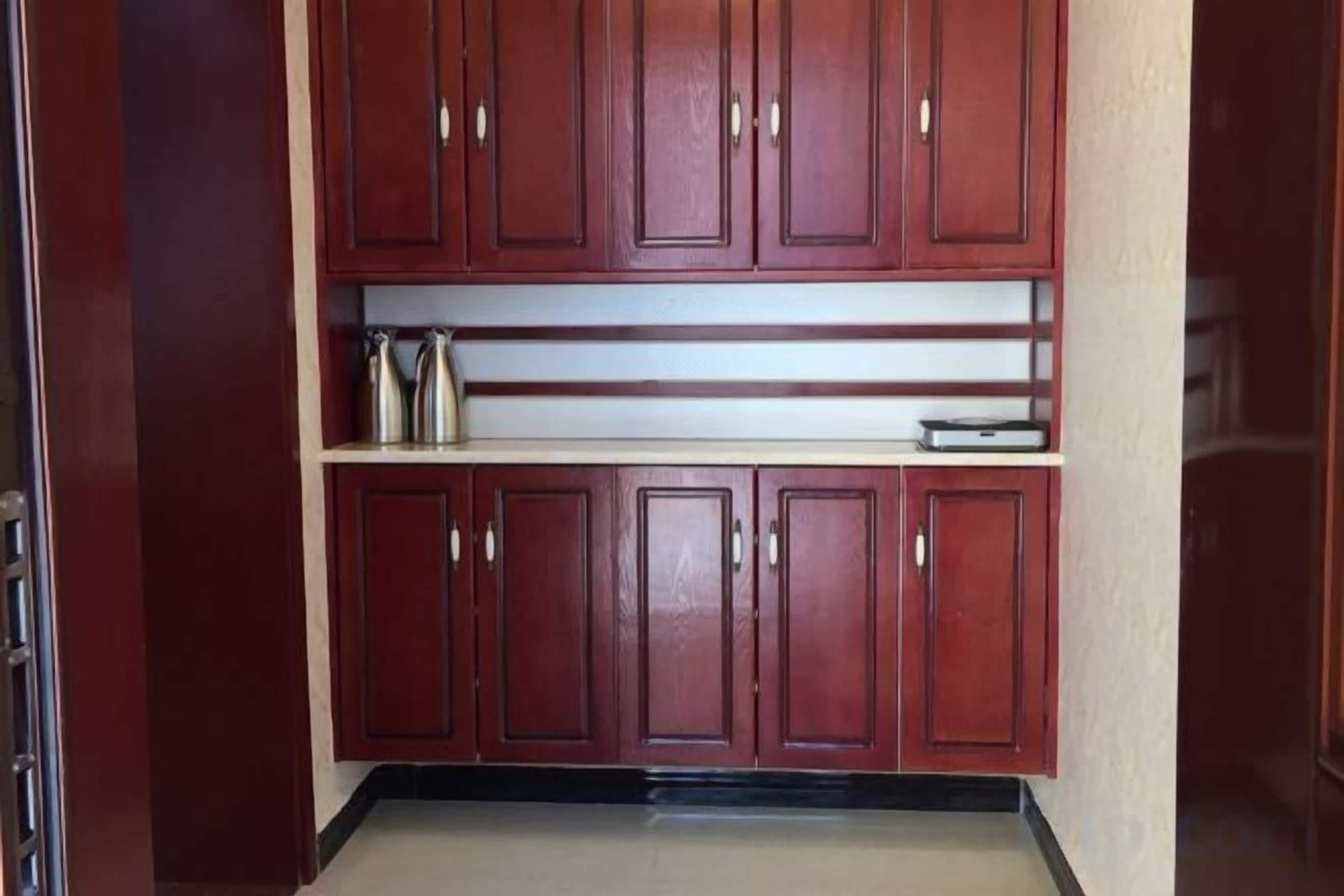 A kitchen with wooden cabinets, a countertop, and a stainless steel kettle.
