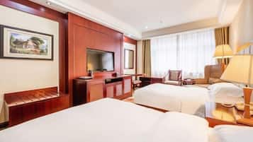 A hotel room with two beds, a TV, a desk, and a chair.