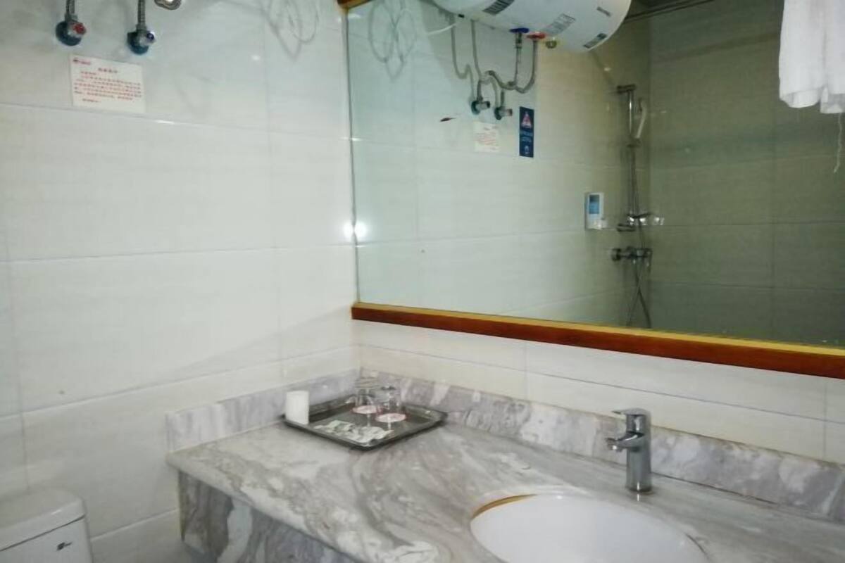 A bathroom with a marble sink, a mirror, and a shower area.
