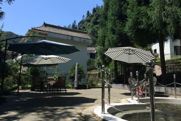 Un patio con mesas al aire libre, sombrillas y una fuente.