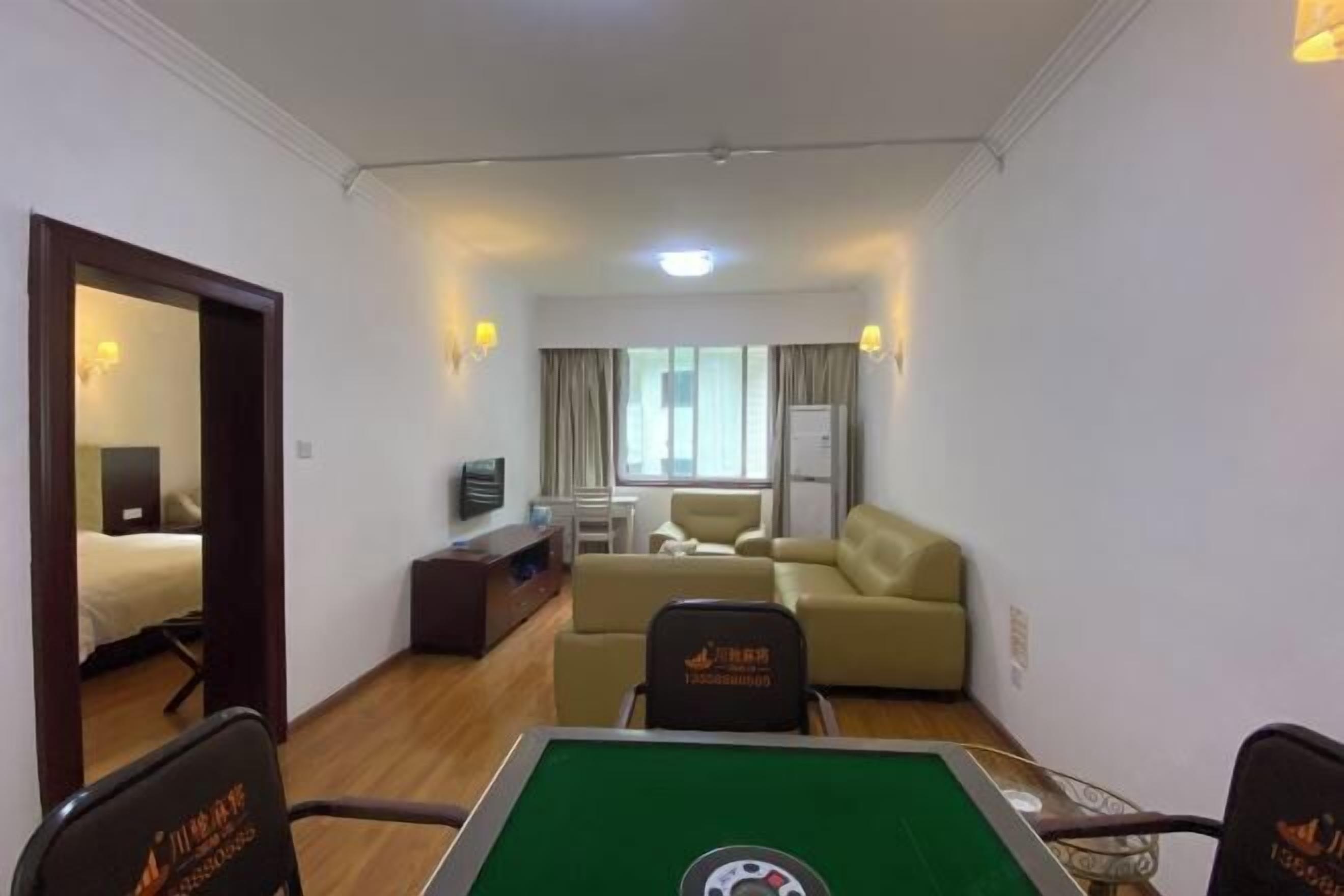 A hotel room with a green pool table, a sofa, a television, and a window with curtains.
