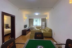 A hotel room with a green pool table, a sofa, a television, and a window with curtains. - Xiling Shanzhuang Hotel (Dayi)