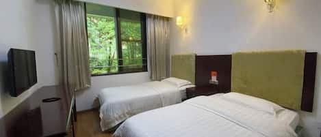 Habitación de hotel con dos camas, un televisor, una ventana con cortinas e iluminación en la pared.