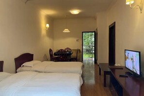 A hotel room with two beds, a dining area, and a TV. - Xiling Shanzhuang Hotel (Dayi)