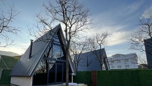 Et moderne hus med skråt tag, store vinduer og et lille udendørs område med trapper, der fører op til en gul dør.