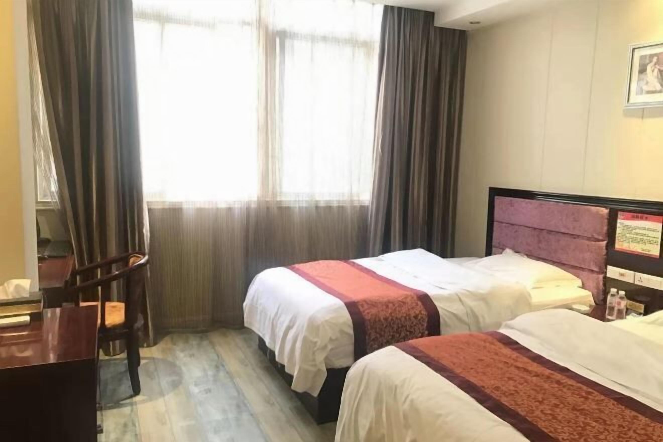 Une chambre d’hôtel avec deux lits, un bureau et une chaise.