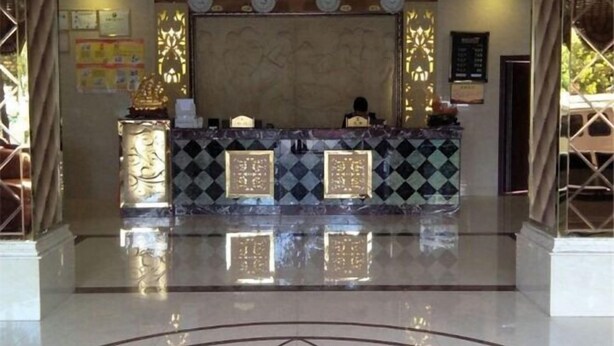 A reception area with a check-in counter, decorative panels, and a large wall with a mural. - Chongqing Hotel (Qinglong)