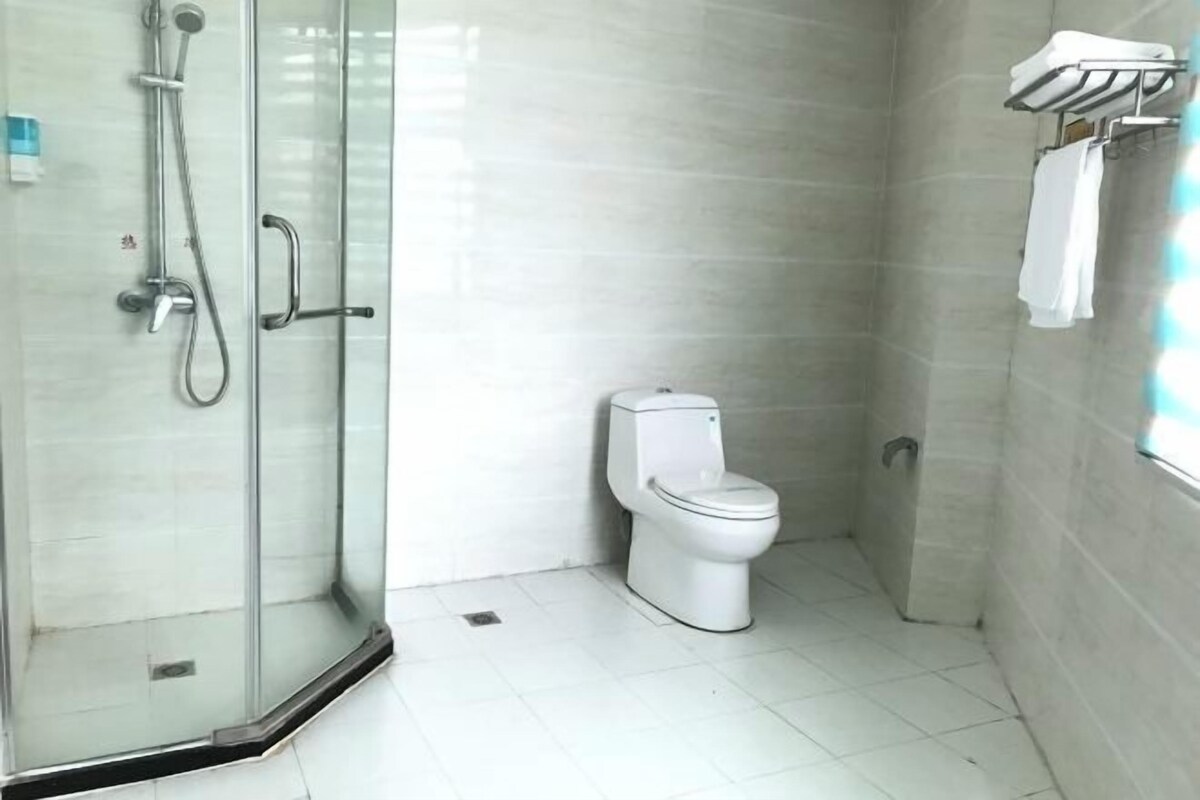 A bathroom with a glass shower enclosure, a toilet, and a towel rack.