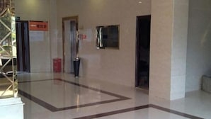 A clean, modern lobby with a polished floor, a reception desk, and a directional sign. - Chongqing Hotel (Qinglong)