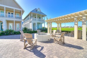 Eine Terrasse mit Sitzgelegenheiten im Freien, einer Feuerstelle und Blick auf einen Golfplatz.