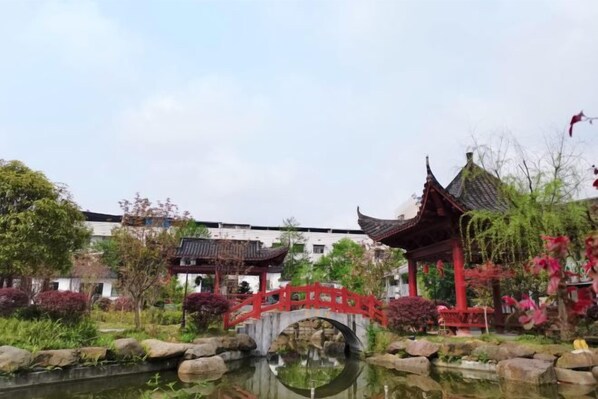Un jardín chino tradicional con un puente rojo, un pabellón y un estanque.