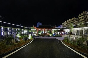 A traditional building with a red roof, surrounded by a well-lit pathway and greenery. - Dongjiangyuan Hotel (Zixing Dongjiang Lake) (Zixing)