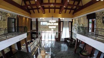 Un vestíbulo amplio con techo alto, una escalera central y un mostrador de recepción.
