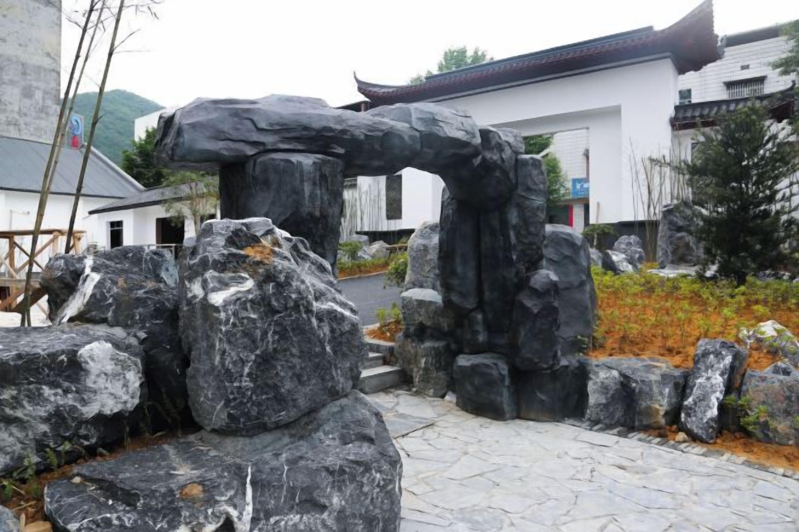 Un edificio tradicional con techo de tejas y un camino de piedra que lleva a una formación rocosa.