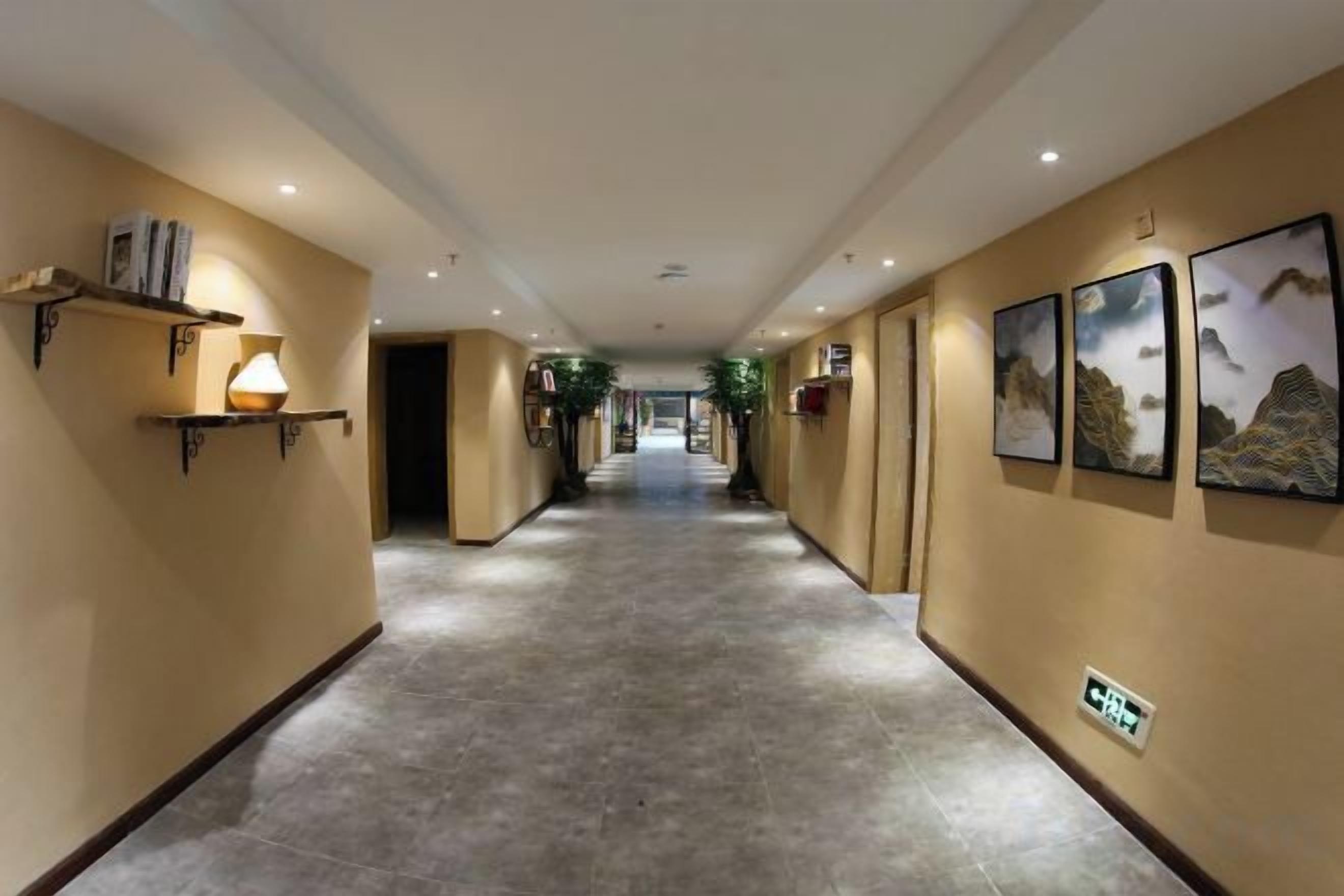 Un pasillo de hotel con piso de baldosas, obras de arte colgadas en la pared y un mostrador de recepción.