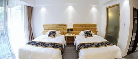 A hotel room with two beds, a wooden headboard, a nightstand, and a large window with curtains.