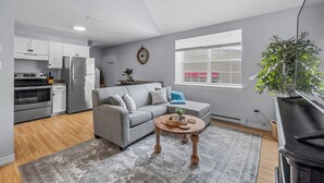A modern kitchen with stainless steel appliances, a grey sofa, and a wooden coffee table. - Harbourview Loft B Two Bedroom Loft Apartment Located in Downtown Summerside (Summerside)