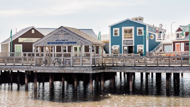 A wooden pier leading to a building labeled "SPINNAKERS LANDING" with a sign for "SUMMERSIDE SOUVENIRS & TRAVEL". - Harbourview Loft B Two Bedroom Loft Apartment Located in Downtown Summerside (Summerside)