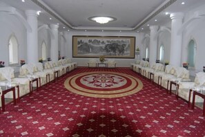 A conference room with a red carpet, white chairs, and a large painting on the wall. - Dongfang Hotel (Rushan)