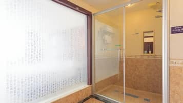 A hotel room with a sliding glass door leading to a shower area.