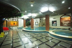 A hotel lobby with a large indoor pool, a reception desk, and a staircase leading to the upper floors. - Dongfang Hotel (Rushan)