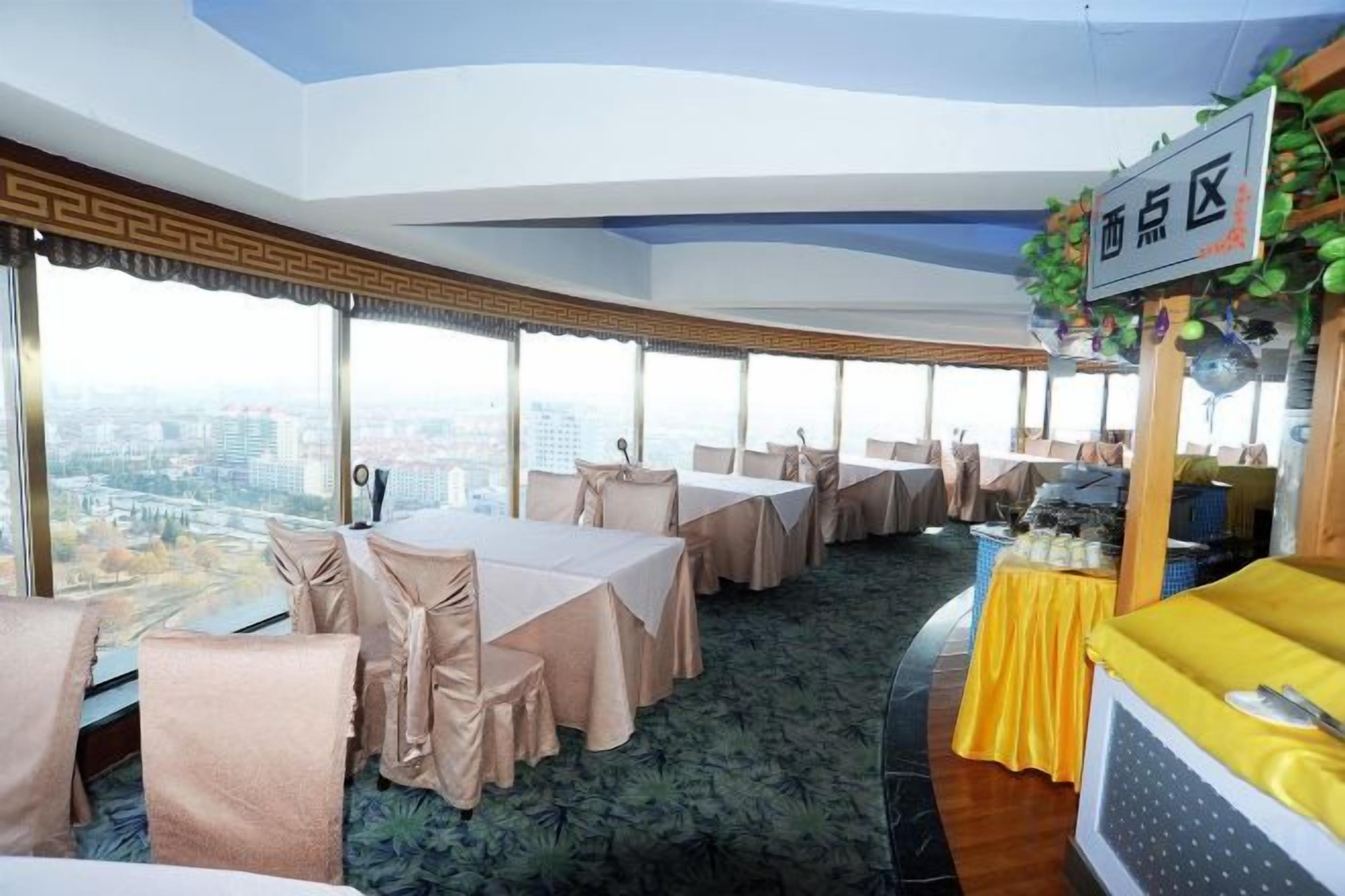 Une salle de conférence équipée de tables et de chaises, un espace buffet et une vue sur la ville.