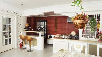 A modern kitchen with a red brick wall, white cabinetry, and a hanging plant.