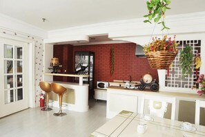 Una cucina moderna con una parete in mattoni rossi, mobili bianchi e una pianta sospesa.