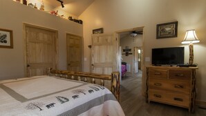 A bedroom with a bed, wooden dresser, and a television. - Tree House Suite at the Calhoun House Inn & Suites (Bryson City)