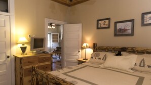 Une chambre à coucher avec un lit, un bureau avec un ordinateur, une lampe et des tableaux encadrés accrochés au mur.