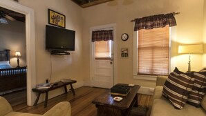 A living room with a television, a couch, a coffee table, and a door with windows. - Toy Box Suite at the Calhoun House Inn & Suites (Bryson City)